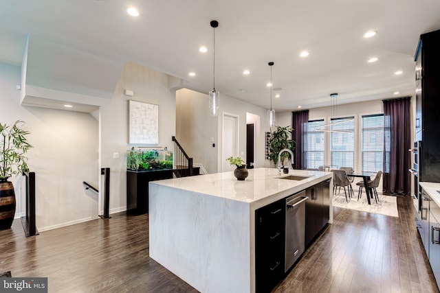 kitchen with a sink, stainless steel dishwasher, dark wood-style flooring, a kitchen island with sink, and recessed lighting
