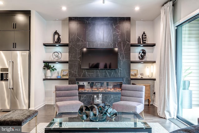 living area featuring wood finished floors, baseboards, recessed lighting, and a high end fireplace