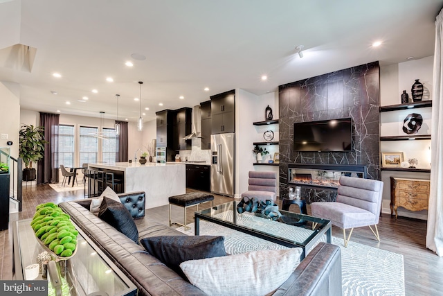 living area with a high end fireplace, recessed lighting, and wood finished floors