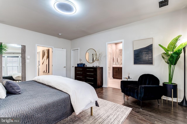 bedroom featuring dark wood-style floors, ensuite bath, and baseboards