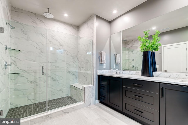 full bath featuring a shower stall, double vanity, marble finish flooring, and recessed lighting
