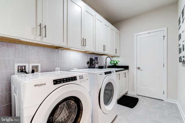 laundry area featuring cabinet space, light tile patterned flooring, washing machine and dryer, and baseboards