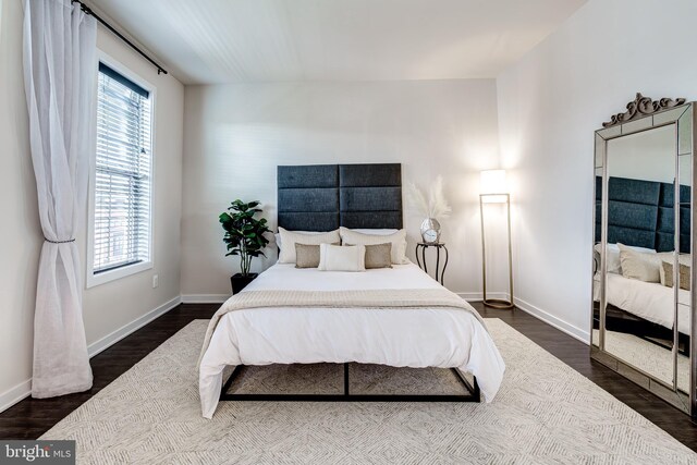 bedroom featuring multiple windows, dark wood finished floors, and baseboards
