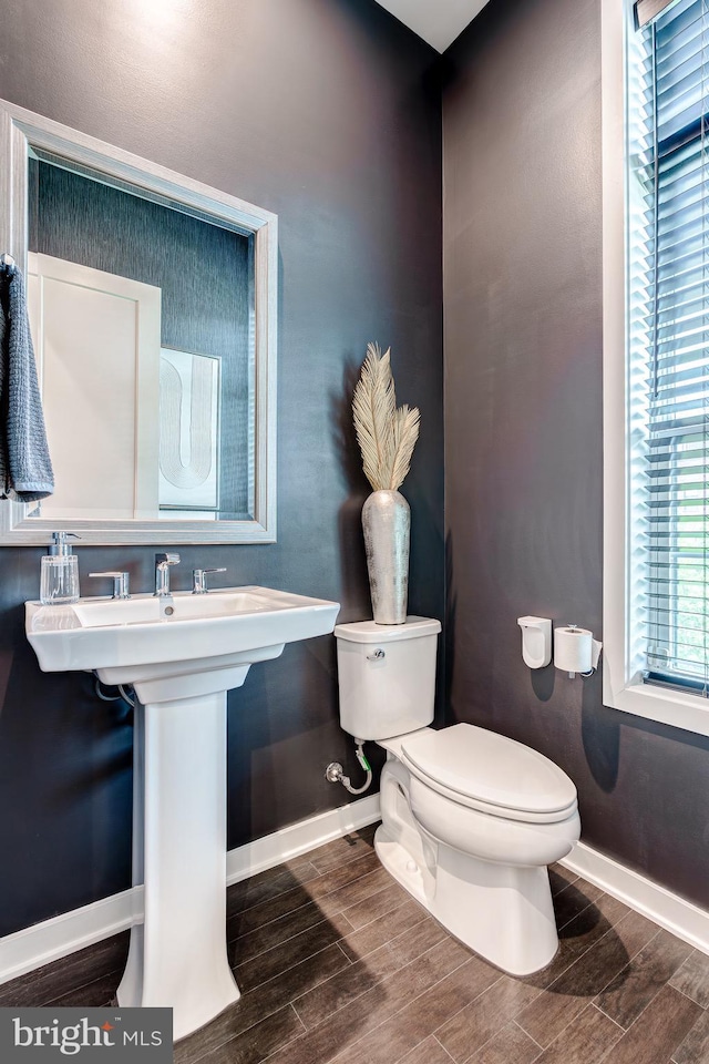 bathroom with toilet, baseboards, and wood finish floors