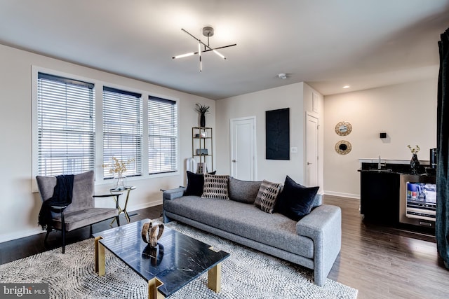 living room featuring baseboards, wine cooler, wood finished floors, and a chandelier