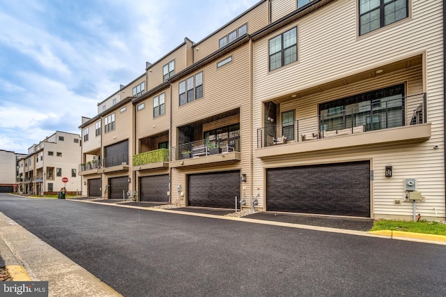 view of property with an attached garage, driveway, and a residential view