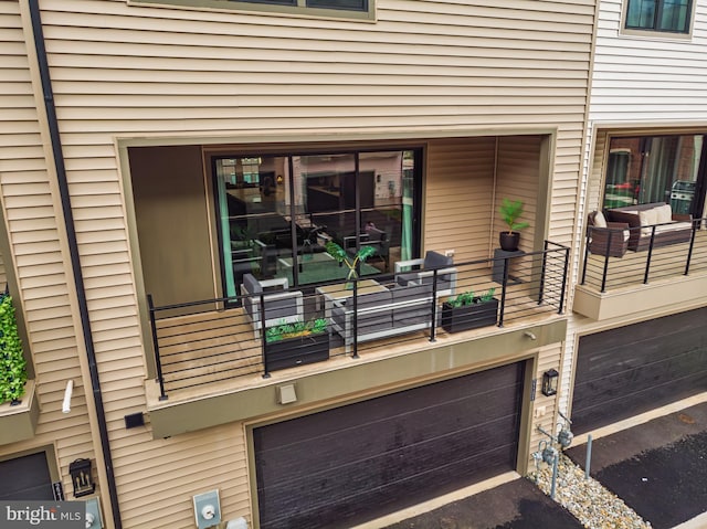 property entrance with an attached garage, asphalt driveway, and a balcony