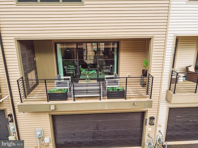 view of exterior entry with a garage and a balcony