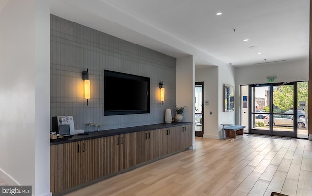 living room with an accent wall, recessed lighting, light wood finished floors, and baseboards