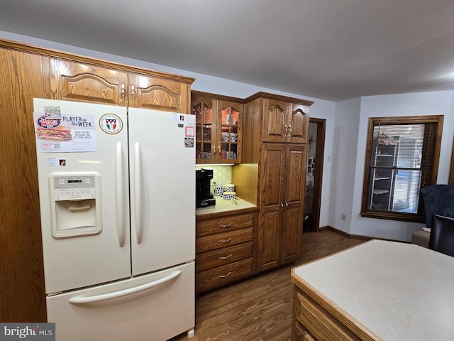 105 Woodview Dr, Harrington, DE 19952 - kitchen with white refrigerator with ice dispenser, dark wood finished floors, glass insert cabinets, light countertops, and brown cabinetry