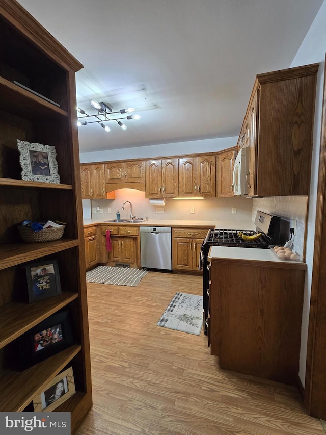 105 Woodview Dr, Harrington, DE 19952 - kitchen with appliances with stainless steel finishes, a sink, light wood-style floors, light countertops, and brown cabinets