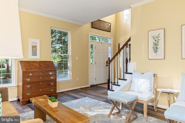 foyer with baseboards, wood finished floors, ornamental molding, and stairway