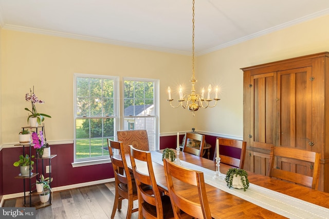 dining space featuring a chandelier, ornamental molding, wood finished floors, and baseboards