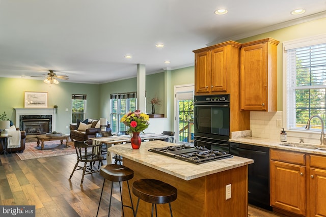 kitchen with a sink, black appliances, a center island, a premium fireplace, and a kitchen bar
