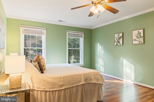 bedroom with wood finished floors, crown molding, baseboards, and ceiling fan