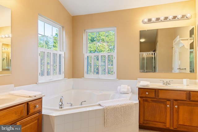 bathroom featuring a stall shower, a garden tub, and two vanities