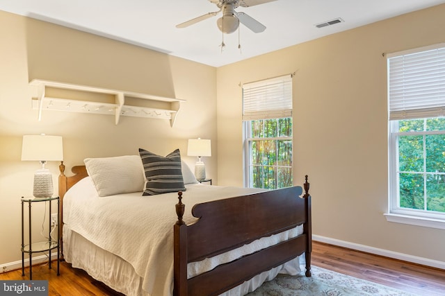 bedroom featuring multiple windows, wood finished floors, and baseboards
