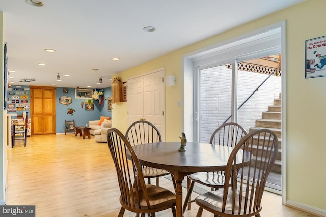 dining room with light wood finished floors, recessed lighting, baseboards, and stairs
