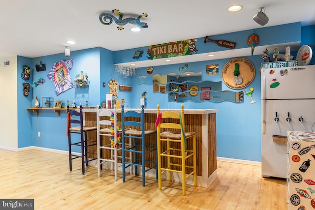 indoor dry bar featuring freestanding refrigerator, wood finished floors, recessed lighting, and baseboards
