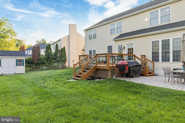 back of property with a storage shed, a lawn, an outbuilding, a wooden deck, and a patio