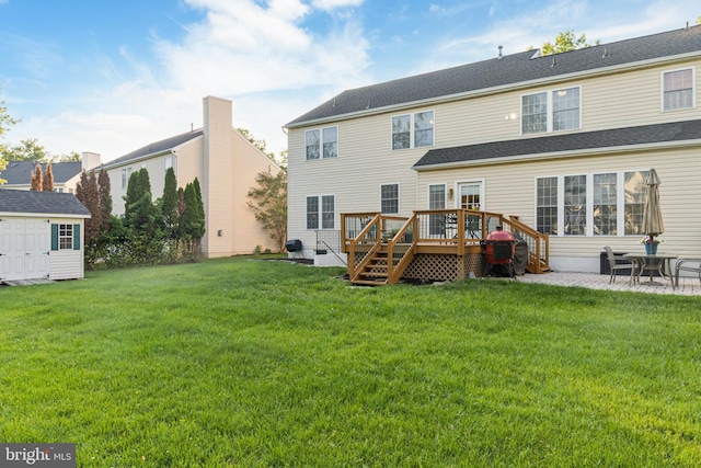 rear view of house with a deck, a yard, a patio area, and an outbuilding
