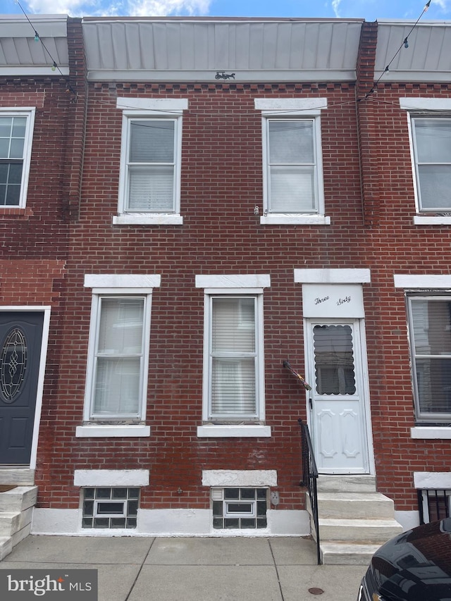 view of property featuring entry steps and brick siding