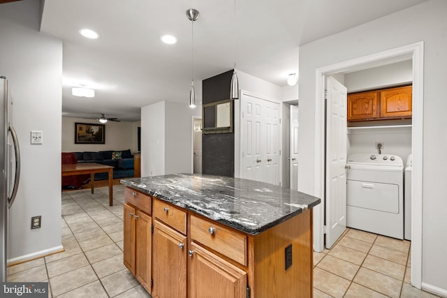 11680 Pellow Circle Ct, Herndon, VA 20170 - kitchen with washer / dryer, light tile patterned flooring, a center island, dark stone counters, and brown cabinets