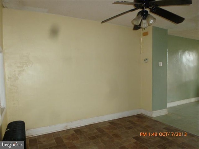 spare room with ceiling fan, baseboards, and stone finish floors