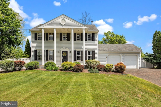 greek revival inspired property featuring an attached garage, asphalt driveway, and roof with shingles