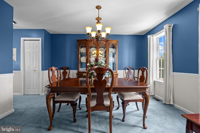 carpeted dining area featuring a chandelier and baseboards