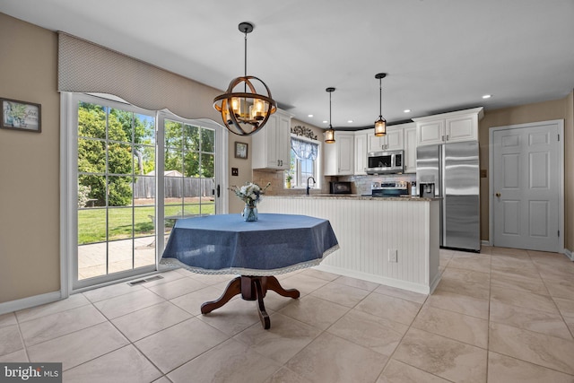 kitchen featuring stainless steel appliances, a sink, white cabinetry, decorative backsplash, and baseboards