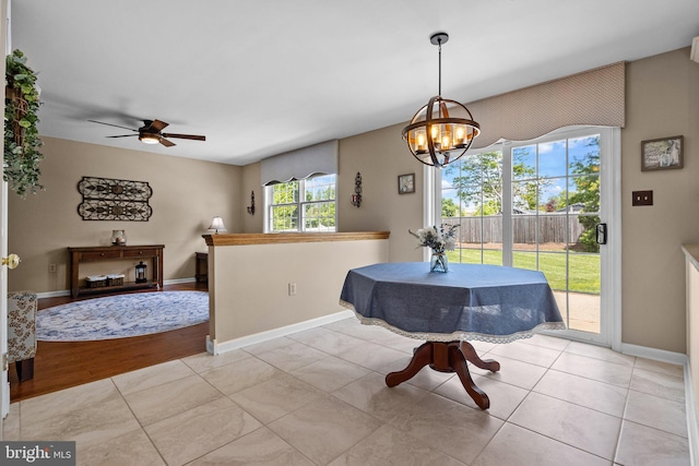 dining room with a chandelier, a ceiling fan, baseboards, and light tile patterned flooring