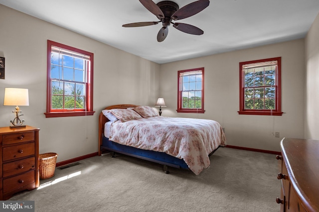 bedroom featuring baseboards, multiple windows, light carpet, and ceiling fan