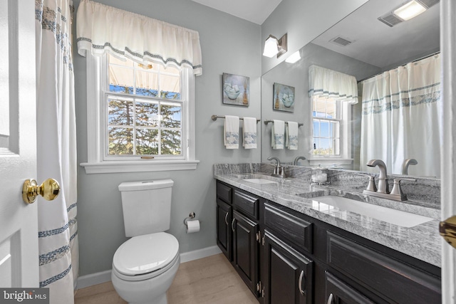 full bath featuring baseboards, toilet, double vanity, and wood finished floors