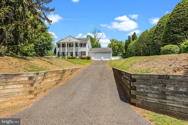 neoclassical home with a garage, asphalt driveway, a front yard, and covered porch