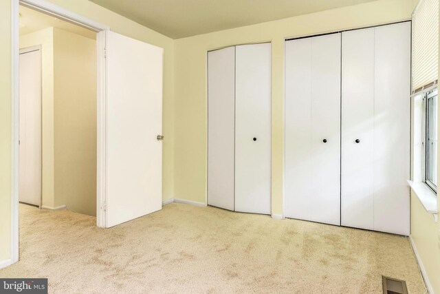 unfurnished bedroom featuring carpet floors, two closets, and baseboards