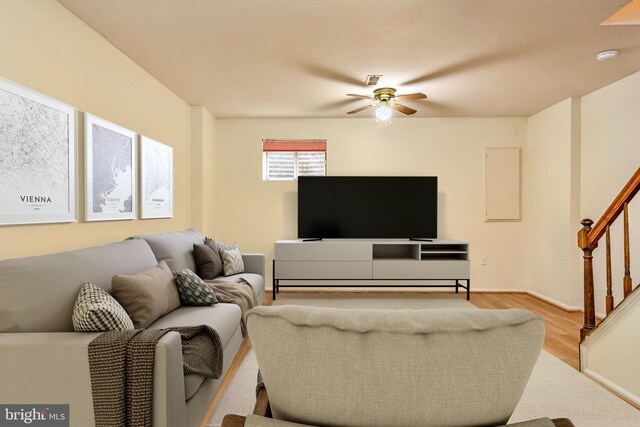 living room with a ceiling fan, stairway, light wood-style floors, and baseboards