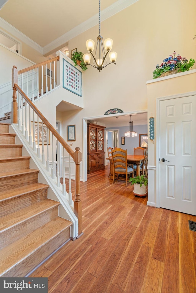 12702 Purdham Dr, Woodbridge, VA 22192 - entrance foyer featuring crown molding, stairway, a chandelier, light wood-style flooring, and a high ceiling
