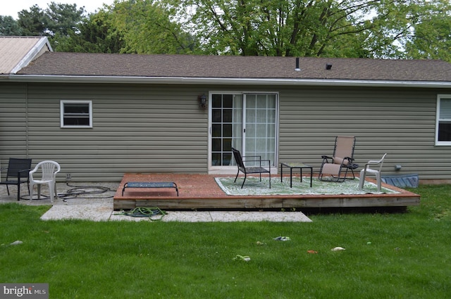 rear view of house featuring a deck, a lawn, and a shingled roof