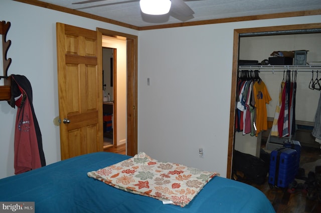 bedroom with a closet, wood finished floors, crown molding, and ceiling fan