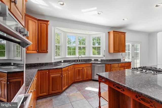 kitchen featuring stainless steel appliances, brown cabinets, dark stone countertops, a sink, and recessed lighting