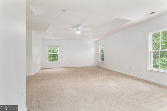 spare room with ceiling fan, healthy amount of natural light, and light carpet