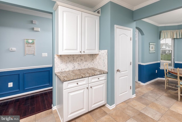 31766 Chablis Ln Unit 76, Lewes, DE 19958 - kitchen featuring arched walkways, light stone counters, white cabinetry, crown molding, and baseboards