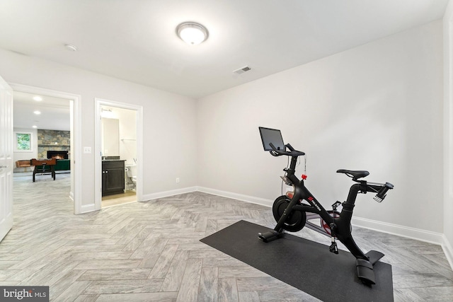 workout area with baseboards and a stone fireplace