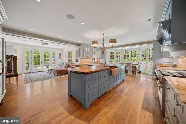 kitchen featuring gray cabinetry, stainless steel range, butcher block counters, french doors, and a sink
