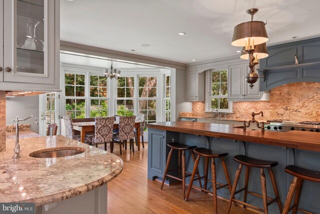 kitchen featuring wood counters, a sink, light wood finished floors, a kitchen breakfast bar, and recessed lighting