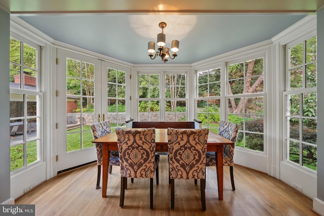 sunroom featuring french doors, a chandelier, and wood finished floors
