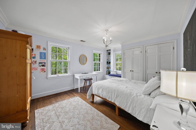bedroom featuring crown molding, two closets, a chandelier, wood finished floors, and baseboards