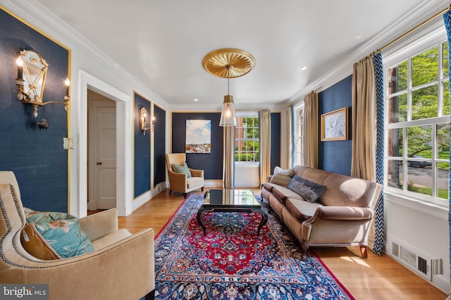living room with wood finished floors, plenty of natural light, ornamental molding, and baseboards