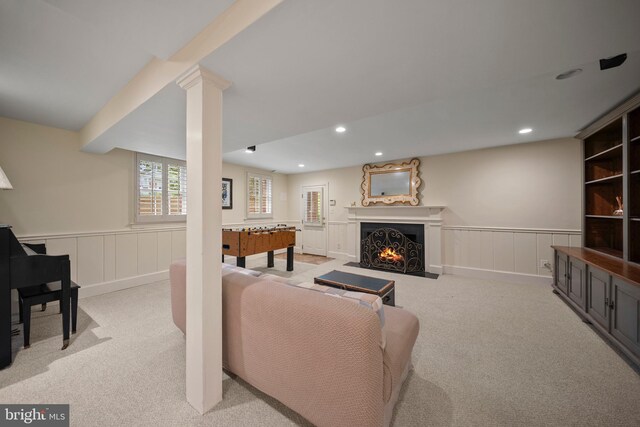 living area with light carpet, wainscoting, a fireplace with flush hearth, recessed lighting, and a decorative wall
